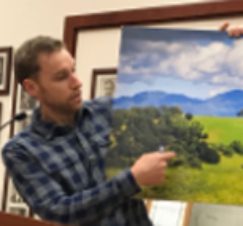 A man holding up an image of a field.