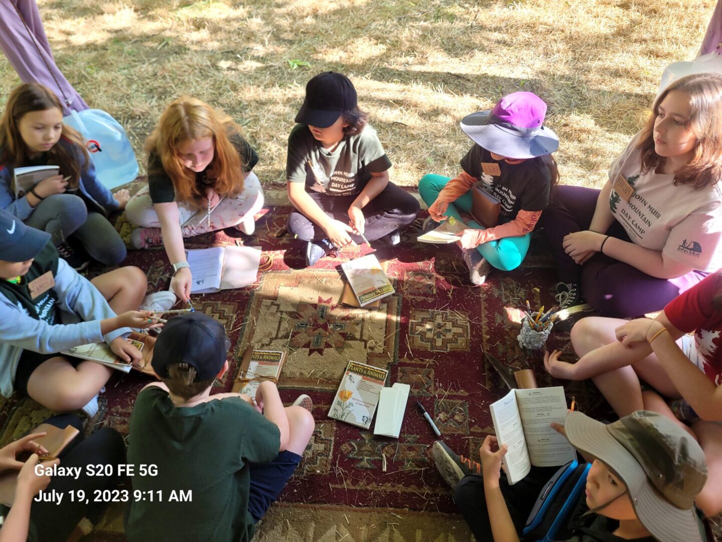 A group of people sitting on the ground reading books.